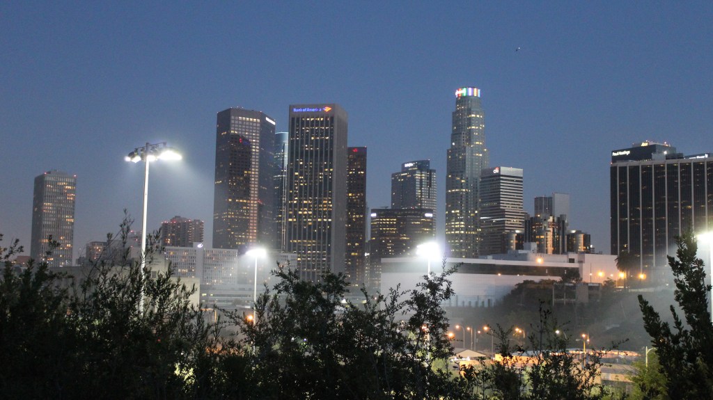 A nighttime view of the Los Angeles Skyline. Skyscrapers are lit against the dusk sky