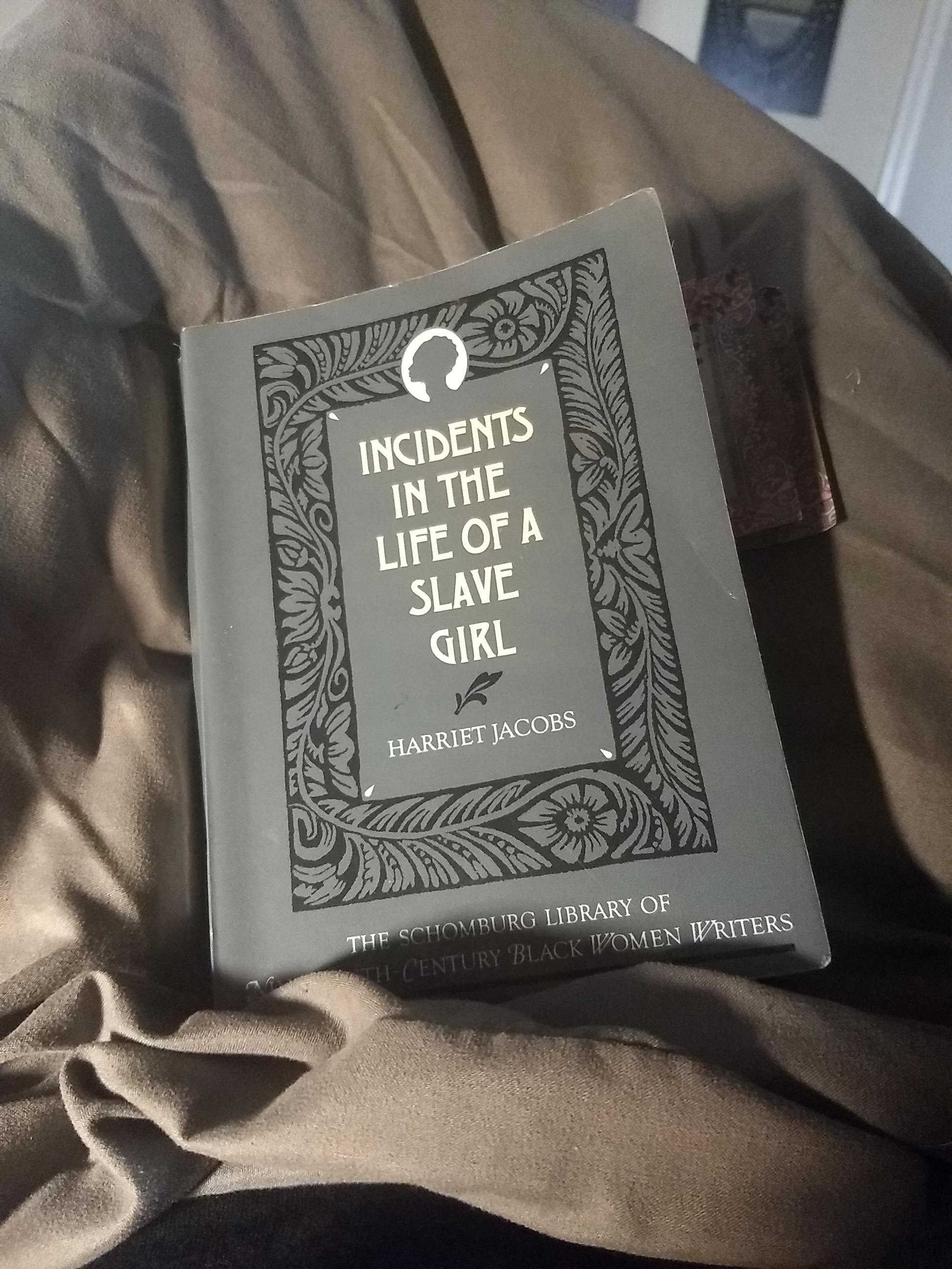 Paperback of Incidents in the Life of a Slave Girl by Harriet Jacobs on a grey fabric background